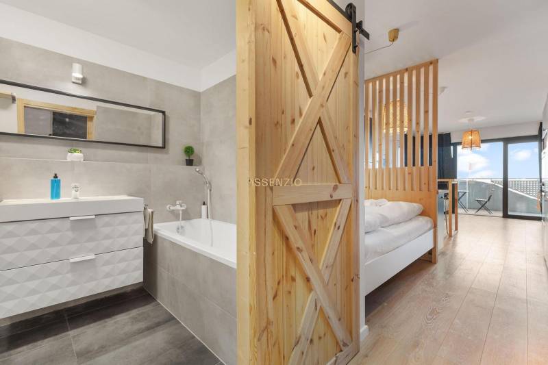 Interiér 1-pokojového bytu s vanou a podlahou s dřevěným dekorem.