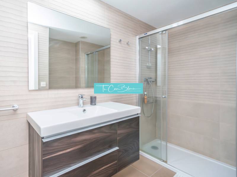 Koupelna v 2pokojovém bytě se sprchovým koutem a zrcadlem nad umyvadlem.