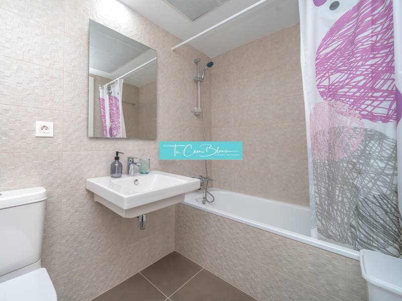 Koupelna v 2-pokojovém bytě s moderními obklady, vanou a umyvadlem.