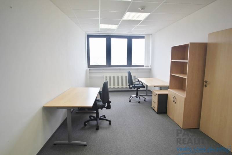 Kanceláře se dvěma pracovními stoly a židlemi, šedý koberec, regál.