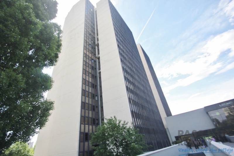 Výšková budova kanceláří na Kutlíkově ulici v Bratislavě - Lúky, částečně obklopená zelení.