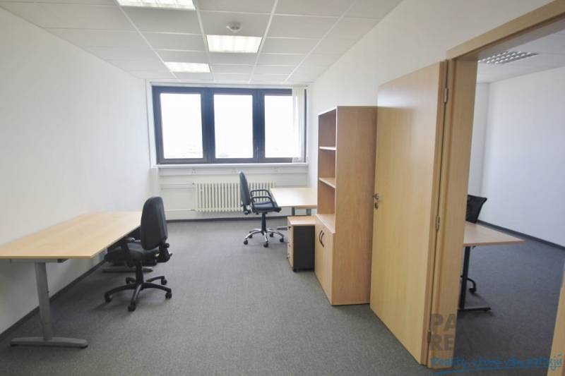 Kanceláře s kancelářským nábytkem, šedým kobercem a světlou stěnou, připravené k práci.