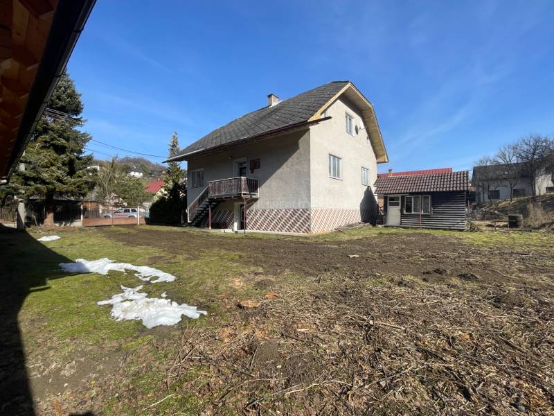 Rodinný dům v Terchové s velkým dvorem a přístřeškem, obklopený trávou a stromy.