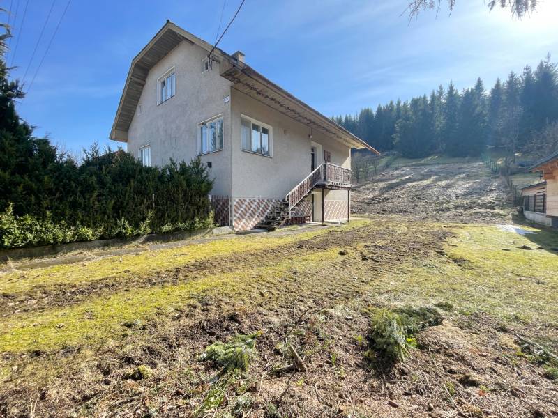 Rodinný dům v Terchové s velkým travnatým pozemkem, obklopený stromy.