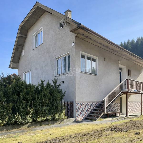 Rodinný dům v Terchové s velkými okny, schodištěm a udržovanou předzahrádkou.