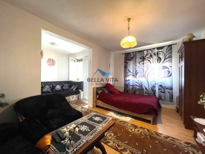 Útulný 1-pokojový byt s podlahou s dřevěným dekorem, postelí a pohovkou s květovaným vzorem.