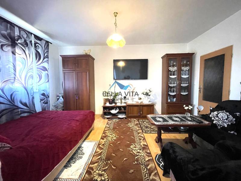 Obývací pokoj v jednopokojovém bytě s podlahou s dřevěným dekorem a nábytkem.