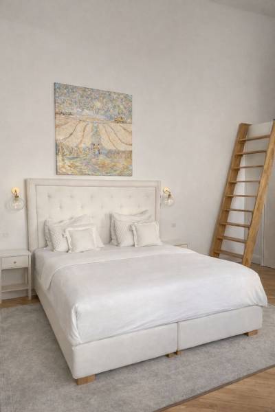 Světlá ložnice s postelí, obrazem na stěně, nočním stolkem a podlahou s dřevěným dekorem.