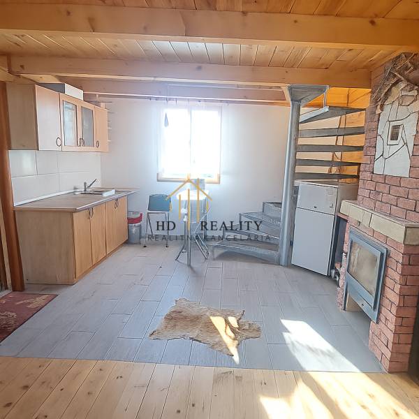 Chata s kuchyní, spirálovým schodištěm a podlahou s dřevěným dekorem.