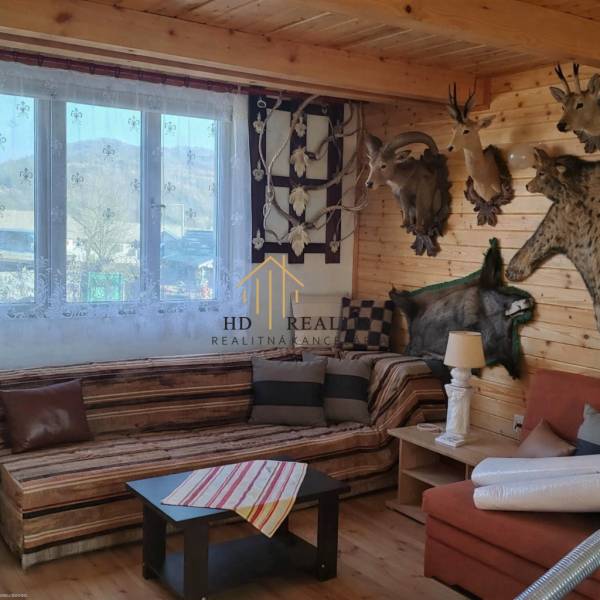 Interiér chaty s trofejemi, dřevěným obložením a podlahou s dřevěným dekorem.