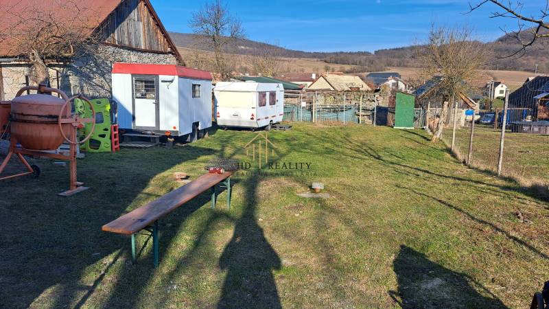 Stavební pozemek v Královcích Krnišově s míchačkou a přívěsnými vozíky na dvoře.