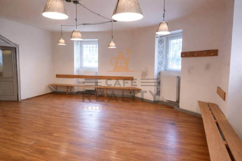 Obchodní prostory s podlahou s dřevěným dekorem, lavicemi a zavěšenými lampami.