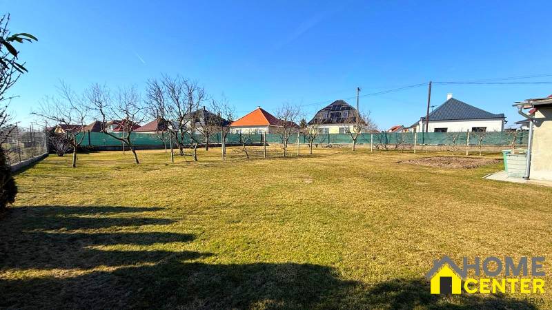 Zahrada rodinného domu v Zemianské Olči s trávníkem a ovocnými stromy.