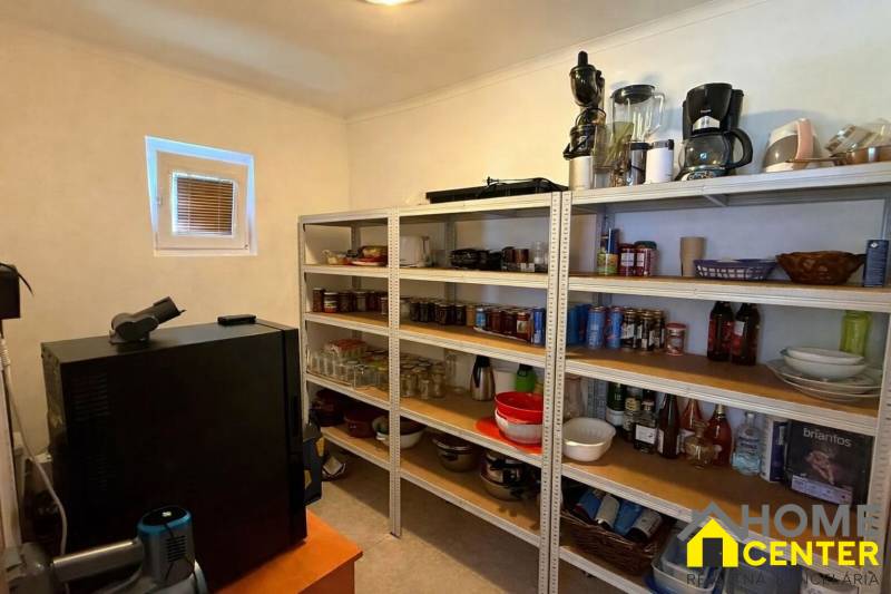 Spižírna v rodinném domě s policemi plnými zásob a kuchyňskými spotřebiči.