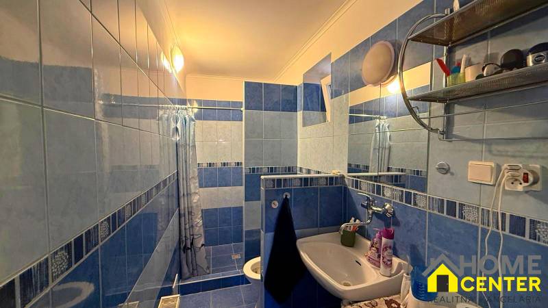 Koupelna v rodinném domě s modro-bílými kachličkami, umyvadlem a sprchovým koutem.