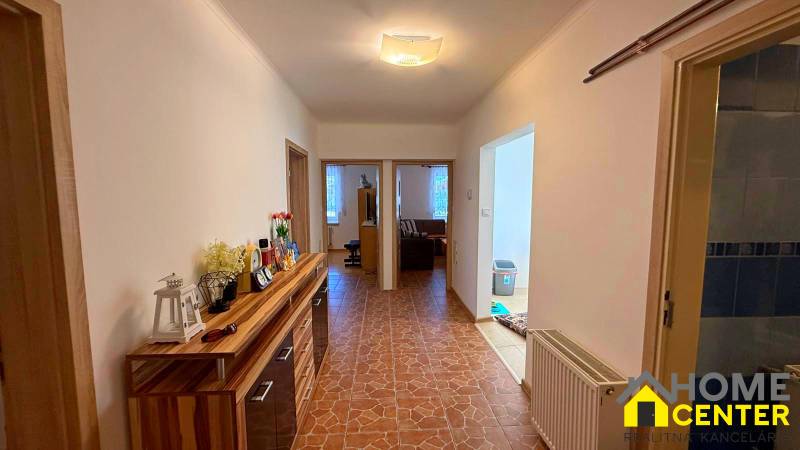 Chodba v rodinném domě s dlažbou a dřevěným dekorem skříňky.