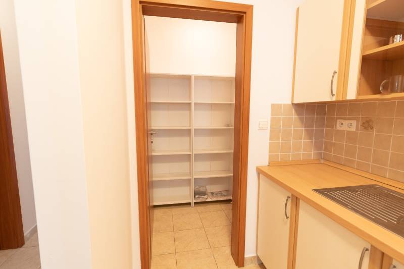 Kuchyně v 2-pokojovém bytě s poličkami a dlažbou, skříňky s dřevěným dekorem.