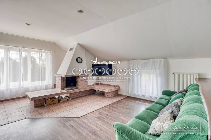 Obývací pokoj s krbem, zelenou pohovkou a podlahou s dřevěným dekorem v rodinném domě.