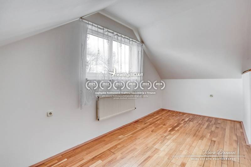 Pokoj v rodinném domě s oknem a podlahou s dřevěným dekorem.