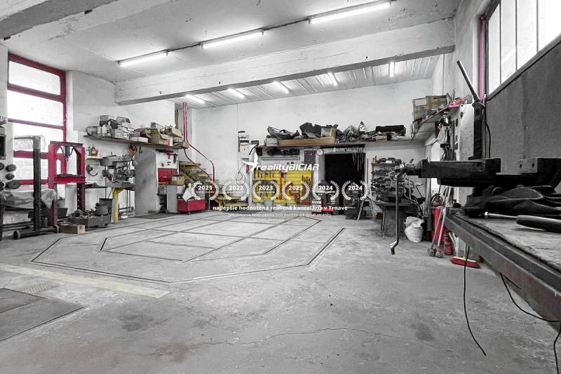 Dílna s nářadím a schody v rodinném domě. Stropy s osvětlením a betonová podlaha.