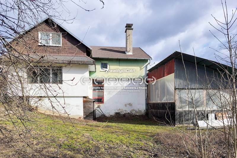 Rodinný dům ve městě Pavlice na ulici Pavlice s plechovou přístavbou a trávníkem.