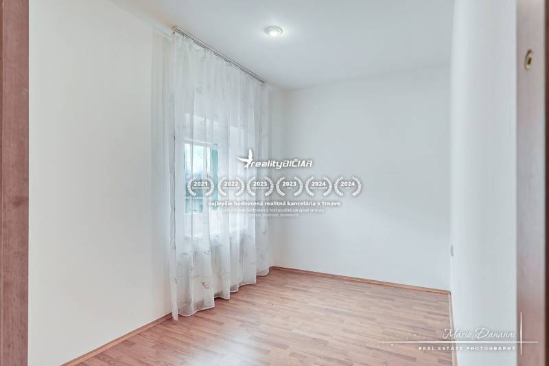 Světlá místnost s podlahou s dřevěným dekorem a záclonami v rodinném domě.