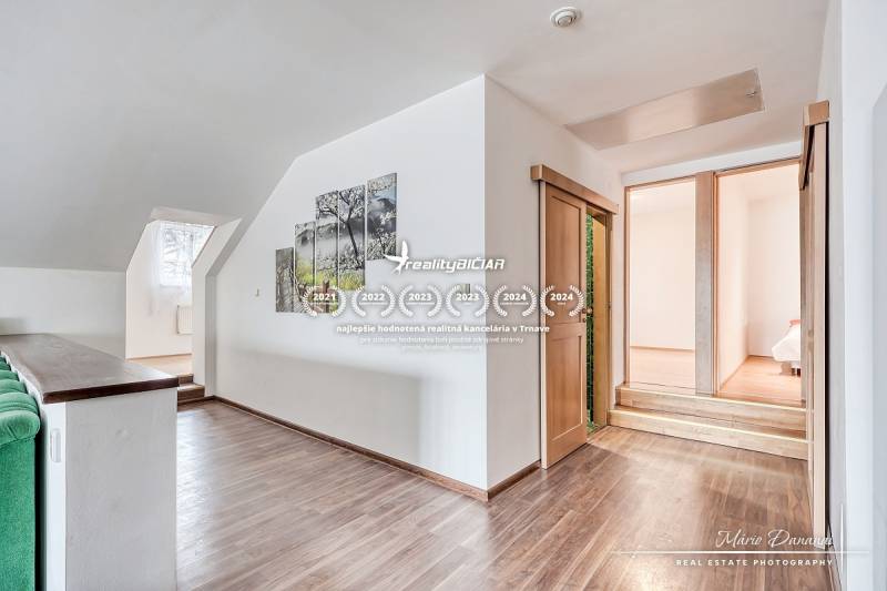 Interiér rodinného domu se schody, dřevěným dekorem podlahy a obrazem na stěně.