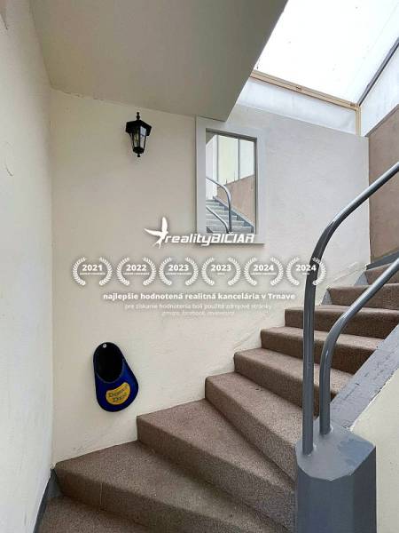 Schodiště v rodinném domě s bílými stěnami a kovovým zábradlím.