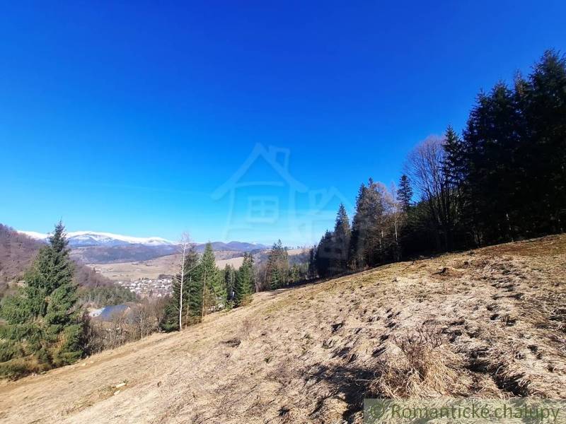 Kopcovitá krajina zemědělských a lesních pozemků kolem obce Hronec se zimní panorámou.