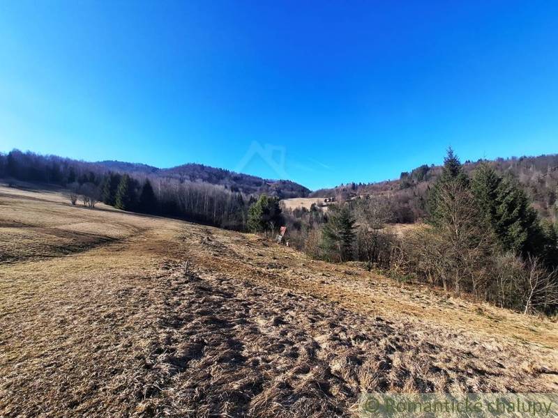 Scenérie zemědělských a lesních pozemků v Hronci s rozlehlými loukami a lesy.