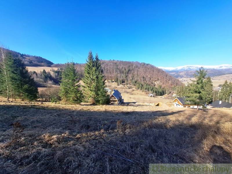 Zemědělské a lesní pozemky v Hronci, obklopené kopci a jehličnatými stromy.