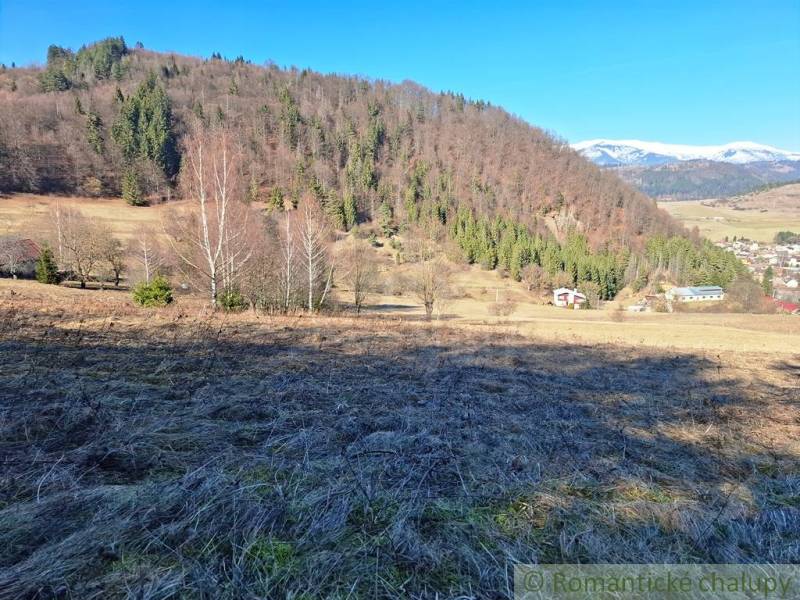 Pohled na Pozemky - bydlení v Hronci s lesy a horami v pozadí.