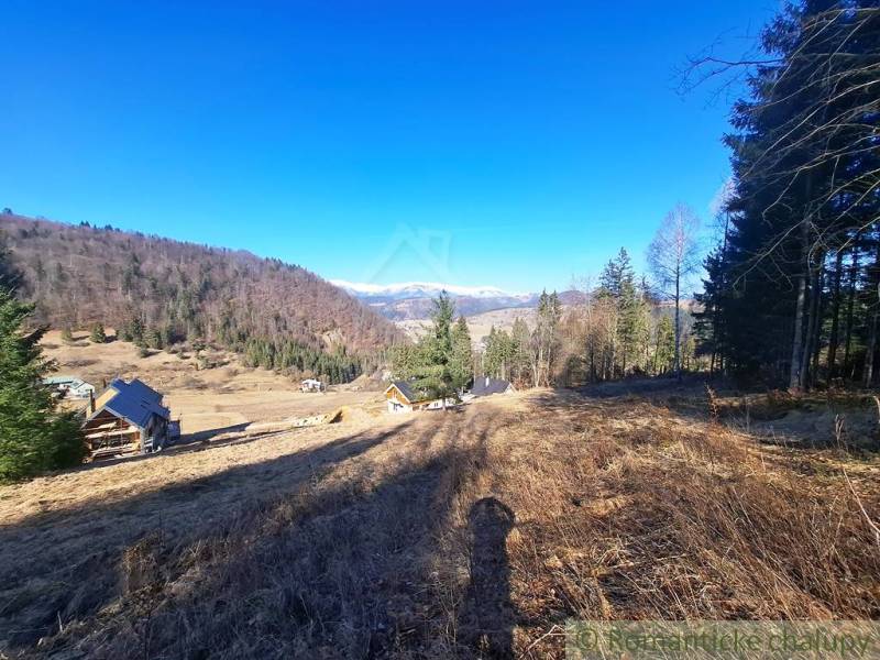 Krajina v obci Hronec, zemědělské a lesní pozemky s výhledem na hory a domy.