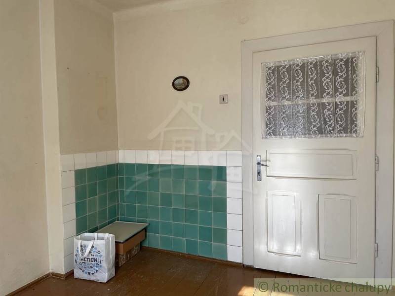 Interiér rodinného domu s bílými dveřmi a zeleno-bílými obkladačkami na stěnách.