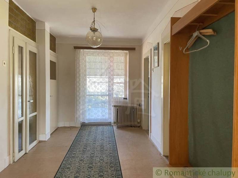 Interiér rodinného domu s podlahou s dřevěným dekorem, závěsem a kobercem.