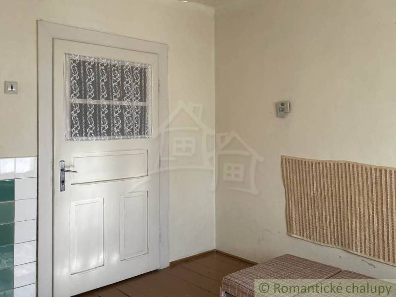 Interiér rodinného domu s bílými dveřmi, obkladem a podlahou s dřevěným dekorem.