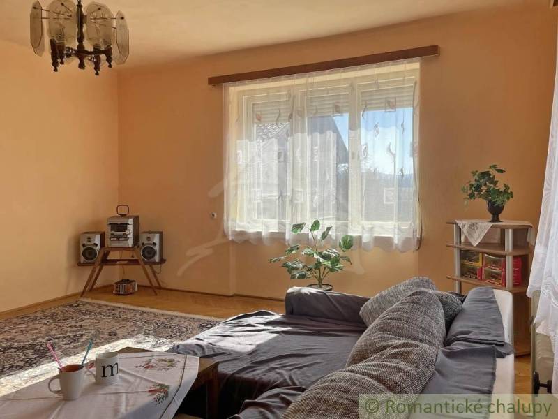 Obývací pokoj v rodinném domě s pohovkou, koberci a hi-fi soupravou.