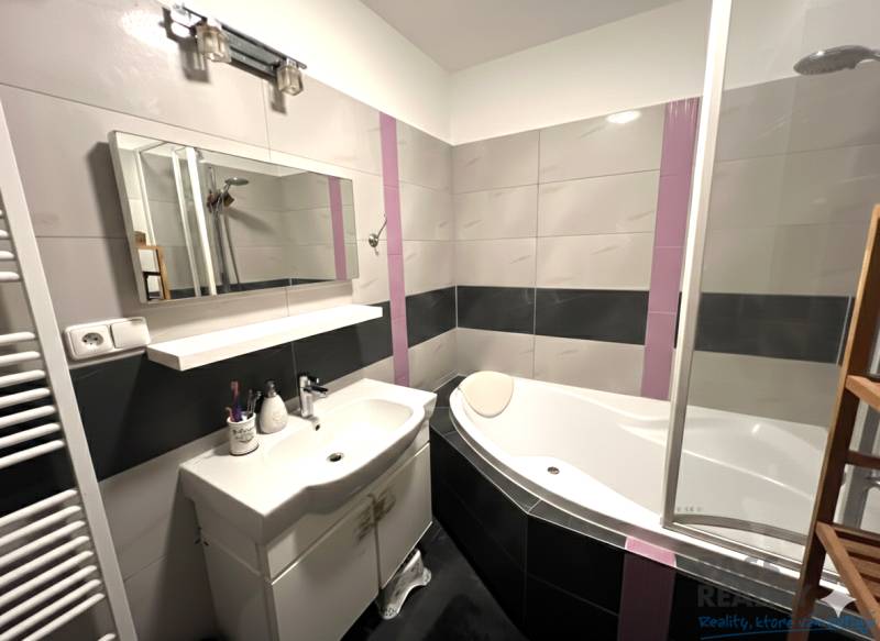 Koupelna s vanou, umyvadlem a zrcadlem v 2-pokojovém bytě.