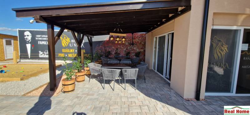 Gastro prostory v Nové Dedince s venkovním posezením a cihlovou zdí.