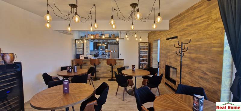 Gastro prostory s podlahou s dřevěným dekorem a závěsnými žárovkami.