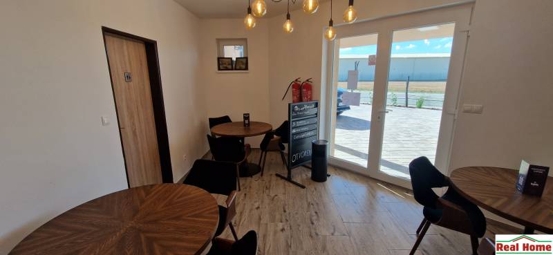 Interiér gastro prostorů s dřevěným dekorem a oknem poskytujícím výhled ven.