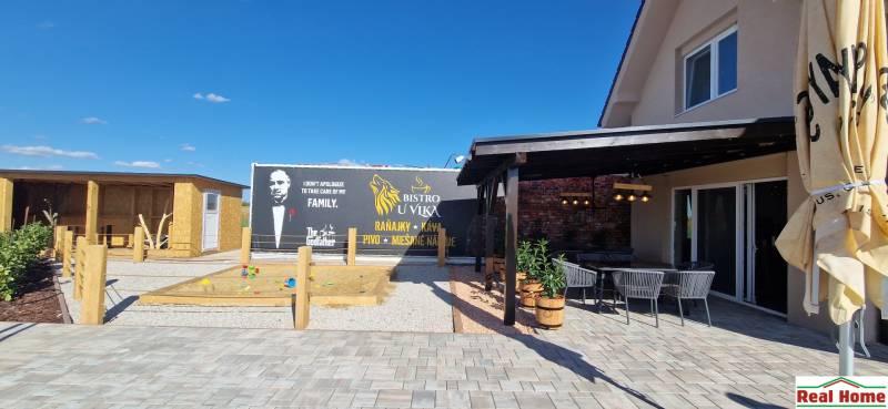 Gastro prostory v Nové Dědince s terasou, pískovištěm a tematickým výhledem.