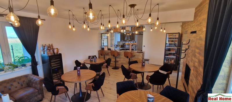 Interiér gastro prostorů s podlahou s dřevěným dekorem a osvětlením žárovkami.