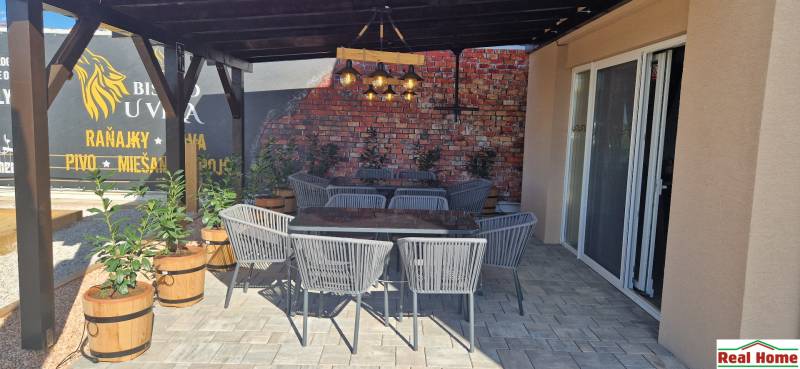 V exteriérových gastro prostorech v Nové Dedince jsou ratanové židle a cihlová zeď.