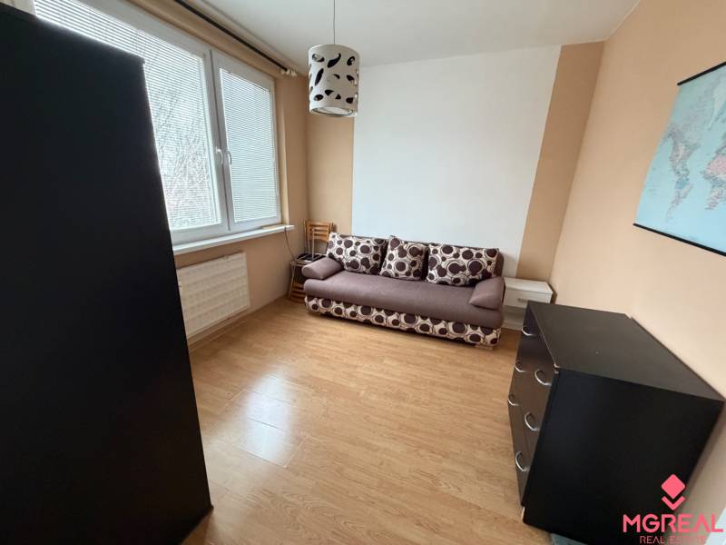 Pokoj s pohovkou, komodou a podlahou s dřevěným dekorem v 3-pokojovém bytě.