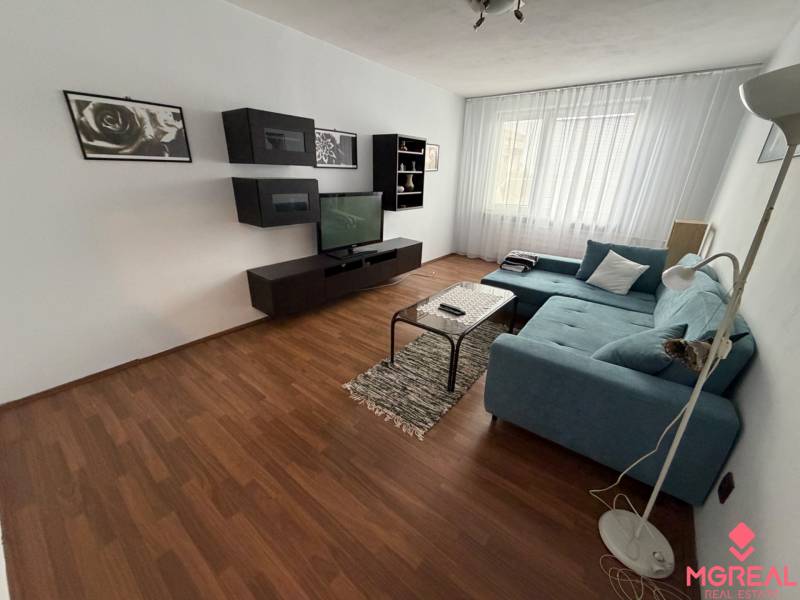 Obývací pokoj s podlahou s dřevěným dekorem a sedačkou v 3-pokojovém bytě.