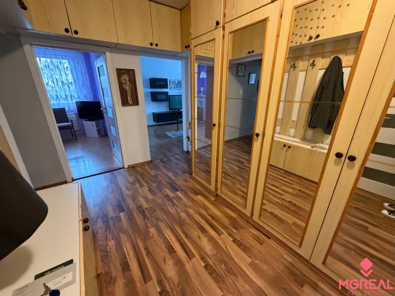 Vstupní hala ve 3-pokojovém bytě s podlahou s dřevěným dekorem a zrcadlovými skříněmi.