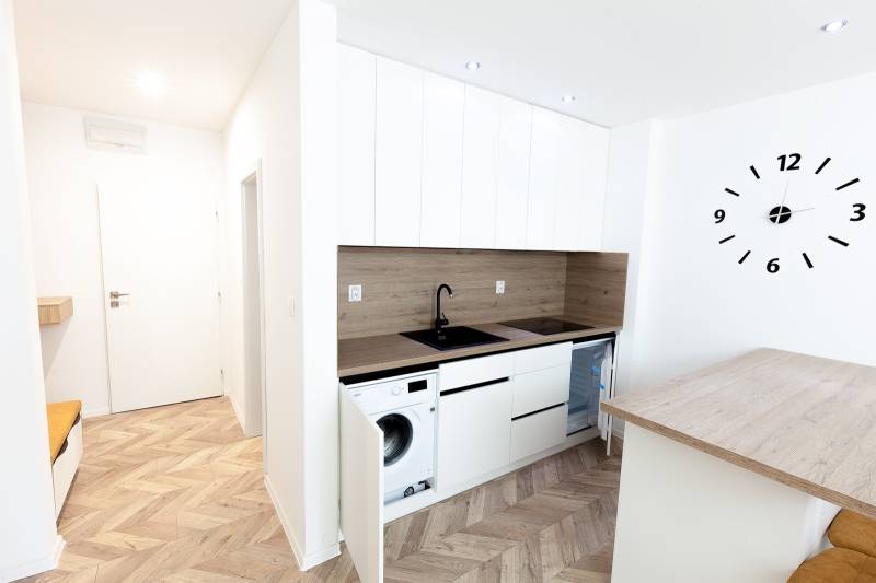Moderně zařízená kuchyně s podlahou s dřevěným dekorem v rekreačním apartmánu.