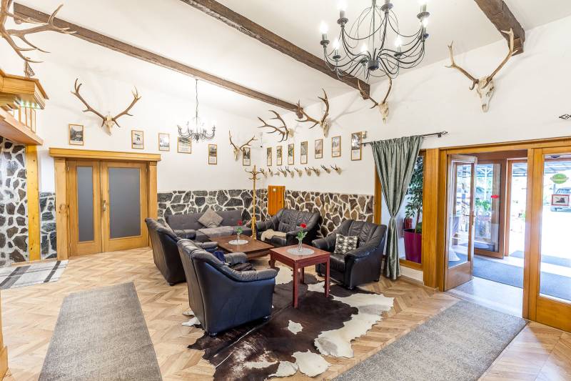 Interiér rekreačního apartmánu s koženou sedací soupravou, rohy a podlahou s dřevěným dekorem.