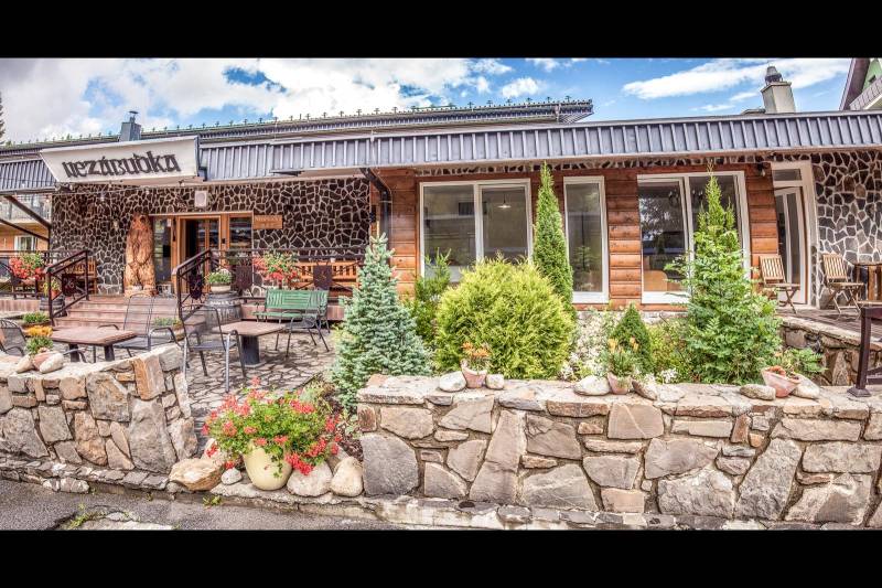 Kamenná fasáda Rekreačního apartmánu ve Štrbě s terasou a květinovou výzdobou.